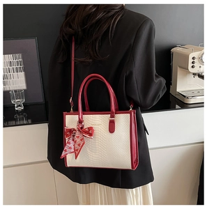 Detail of faux snake skin handbag with red trim and heart print silk scarf on handle