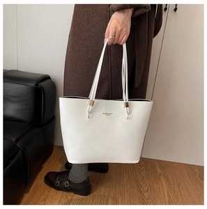 Close-up of white leather tote bag with gold ring hardware and fashion letter print