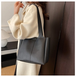 Gros plan d'un sac cabas noir minimaliste avec coutures verticales porté par le modèle