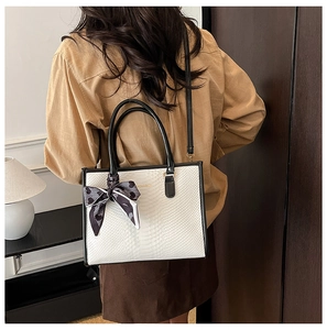 Macro detail of white snakeskin texture leather tote bag with silk scarf and gold logo