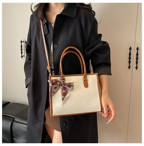 Detail of embossed tote with silk scarf handle and adjustable crossbody strap