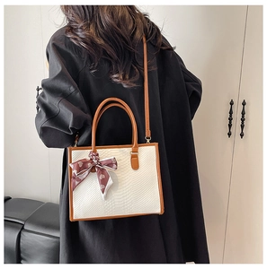 Detailed side view of off-white faux snake texture bag with brown strap and silk scarf