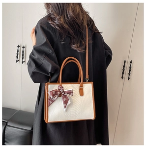 Detail of white snakeskin tote bag with brown leather trim and heart print scarf