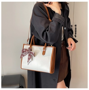 Macro detail of faux snakeskin tote bag with leather trim and heart print silk scarf