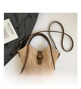 Detail of minimalist bucket bag with unique paper-like texture and bronze twist lock