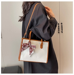 Detail of white snakeskin tote bag with brown handles and a heart pattern scarf