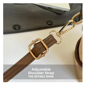 Detail of brown leather adjustable shoulder strap with gold metal buckle and lobster clasp