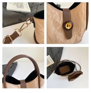 Detail view of large beige bucket bag with brown handles and gold hardware buckle