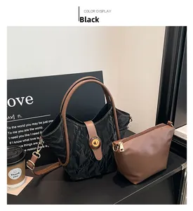 Detail of black pleated tote bag set with brown handles and gold metal twist lock
