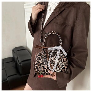 Detail of leopard print crossbody bag with cherry pendant, pearls and lace bow decoration