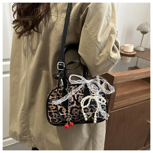 Détails du sac léopard avec nœud en dentelle, breloques perles et pendentif cerise
