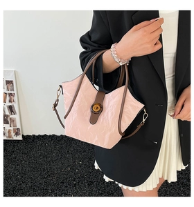 Bolso cubo rosa con textura rugosa, bordes marrones en contraste y cierre de metal retro