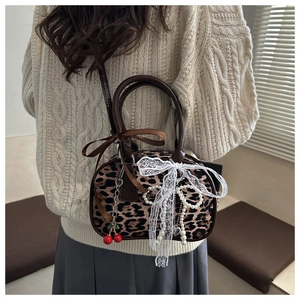 Détail du sac léopard avec un nœud en dentelle blanche et un charm de cerise