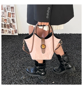 Detalle del bolso tipo cubo rosa plisado con hebilla de ámbar y correa de cuero