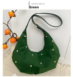 Detail of green suede hobo bag with gold rivet accents on a textured carpet background