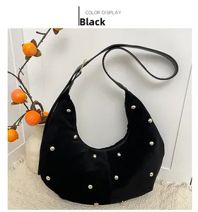 Detail of black suede hobo bag with gold studs and smooth leather strap for winter