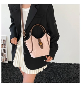 Detail view of pink pleated bucket bag with brown circular handles and textured finish
