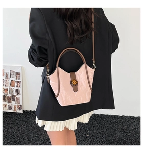 Detail of pink pleated bucket bag featuring brown leather trim and metal twist lock closure