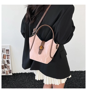 Pink pleated bucket bag with brown handles and twist lock shown on a model