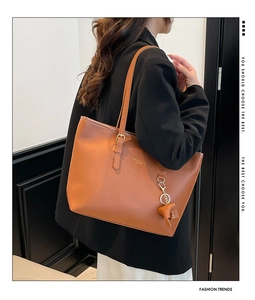 Detail van bruine leren shopper met verstelbare bandjes en een beertje-bedeltje