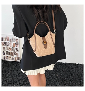 Detailed view of beige shoulder bag with unique pleated texture and vintage metal lock