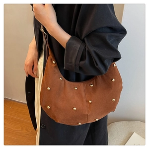 Detail of brown suede hobo bag with gold metal rivets and smooth zipper closure