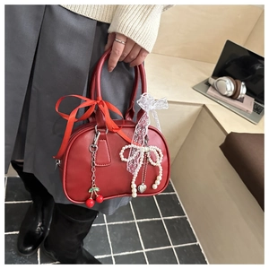 Detail of red leather Boston bag with cherry charms and lace ribbon on a handle