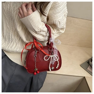 Detail of dark red bow handbag with lace ribbon, cherry charm and pearl pendant