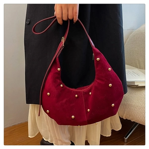 Dettaglio borsa in camoscio bordeaux con borchie dorate e tracolla in pelle regolabile