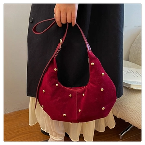 Detailed shot of burgundy suede hobo bag featuring decorative golden metal studs