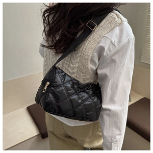 Detail of black quilted puffer shoulder bag featuring adjustable strap and golden hardware