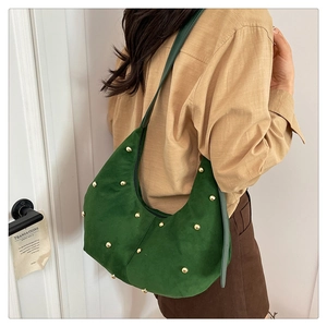 Detail of dark green suede hobo bag featuring decorative gold round rivets and leather strap