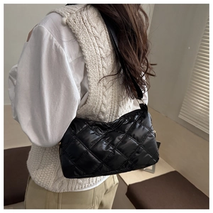 Detail of a black quilted shoulder bag with rhombic stitching and a glossy nylon finish