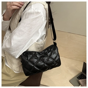 Détail du motif matelassé à losanges sur un sac à bandoulière noir brillant