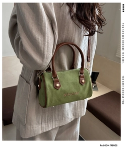 Detail of green suede Boston bag with brown leather handles and golden metal hardware