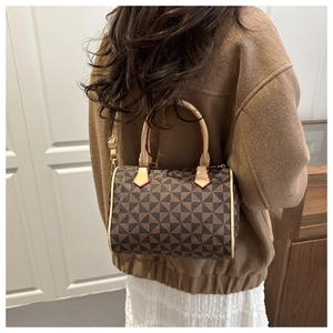 Detail view of the Boston bag's geometric pattern, red edge oil, and golden metal hardware