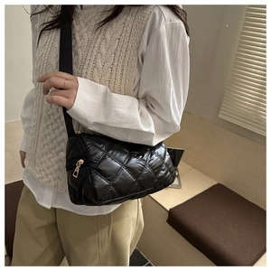 Detail of black quilted nylon shoulder bag with adjustable strap and metal zipper