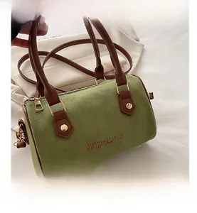 Detail of green suede Boston bag featuring brown leather handles and brand embroidery