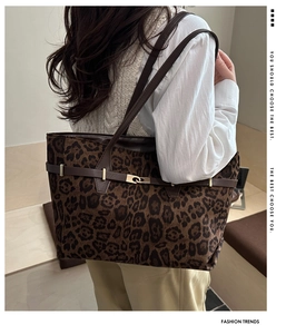 Detail of leopard print tote bag with brown leather straps and gold metal twist-lock closure