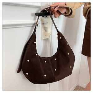 Detail of dark brown hobo bag featuring decorative gold rivets and suede-like fabric texture
