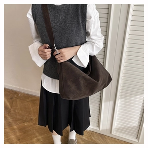 Vue détaillée d'un grand sac hobo en daim marron foncé avec une large bandoulière souple