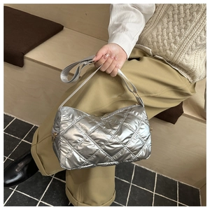 Macro detail of silver quilted metallic fabric with gold zipper and textured wide strap