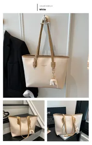Detailed view of white faux leather tote bag with brown straps and elephant charm