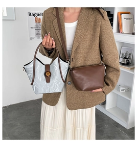 Detalle del bolso tote plateado con textura, ribete marrón y bolso bandolera pequeño