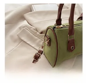 Detail of golden metal hooks and brown leather handles on a green suede Boston bag