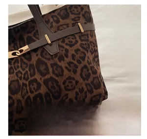 Detailopname van luipaardprint tas met bruine leren riem en gouden metalen gesp