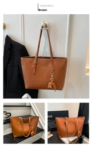 Detail of brown tote bag with gold lettering, shoulder strap buckle and elephant charm