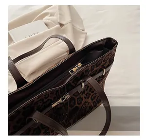 Detailopname van luipaardprint tote bag met gladde gouden rits en bruine leren handgreep