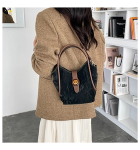 Modelo con bolso fruncido negro y asas redondas marrones en un entorno minimalista