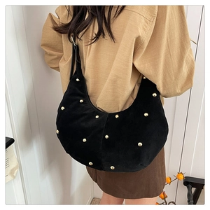 Detail of black suede crescent hobo bag featuring gold studs and adjustable shoulder strap